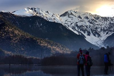 Rear view of people on snowcapped mountains against sky