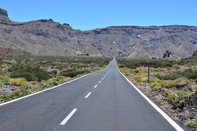 Road leading towards mountains against sky