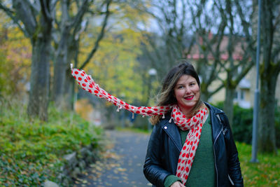 Portrait of smiling young woman standing in park