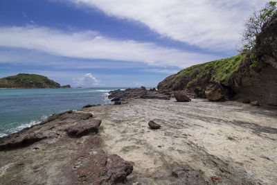 Rock formation on beach against sky