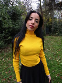 Portrait of beautiful young woman standing against trees