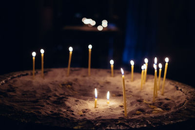 Close-up of illuminated candles in sand