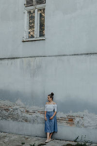 Young woman standing against wall