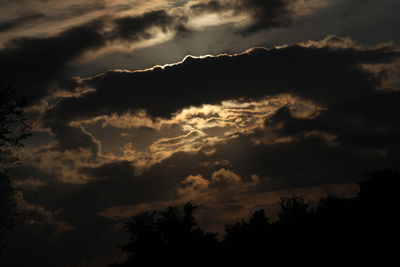 Low angle view of silhouette trees against dramatic sky