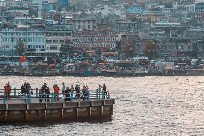 Group of people by sea against buildings in city