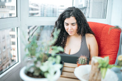 Portrait of young woman sitting on sofa at home