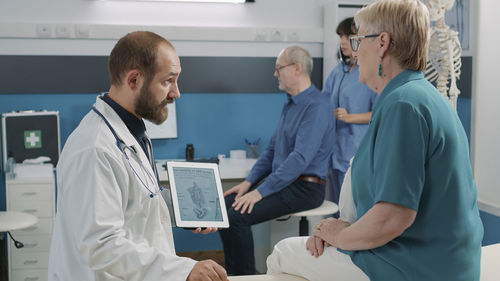 Male doctor with digital tablet explaining female patient in hospital