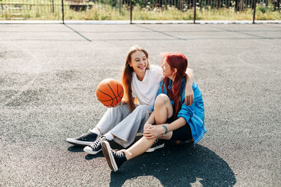 A couple of teenage girls on a sports street court with a basketball lifestyle relax after a game 