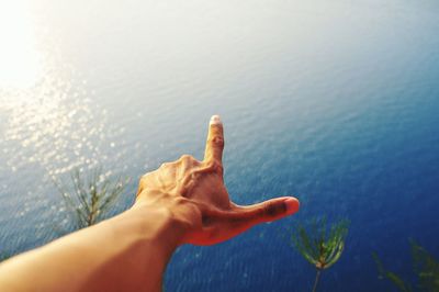 Close-up of hand against lake