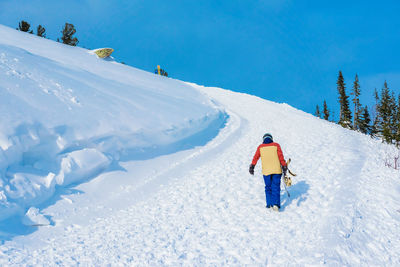 Rear view of man walking on snow covered land