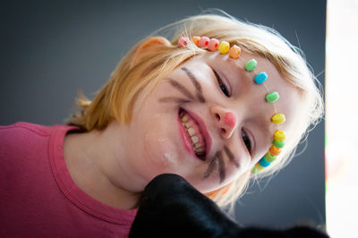 Close-up of smiling girl wearing candies with painted face