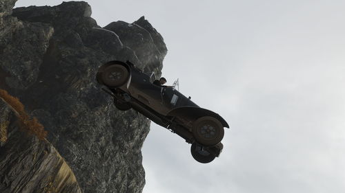 Low angle view of tractor on rock against sky