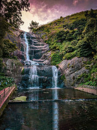 Scenic view of waterfall in forest against sky