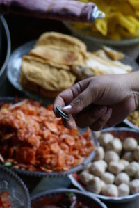 Cropped hand holding coins over food in containers at market stall