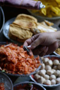 Cropped hand holding coins over food in containers at market stall