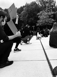 People sitting on footpath by street in city