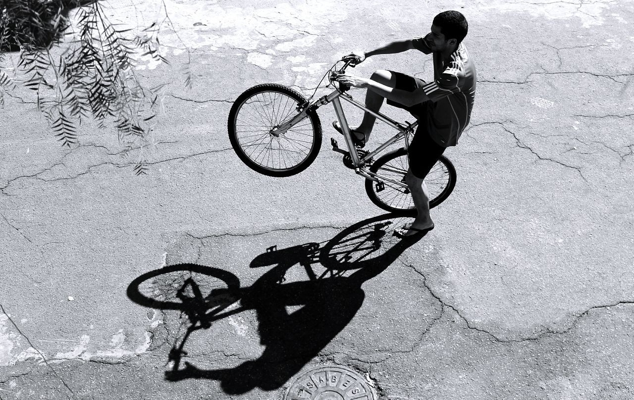 HIGH ANGLE VIEW OF PEOPLE RIDING BICYCLE ON ROAD