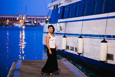 Full length portrait of young woman standing at harbor