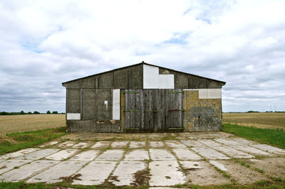 Old barn on field against sky