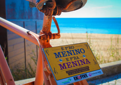 Close-up of information sign against sea