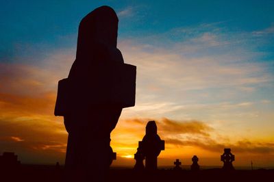 Silhouette people standing against orange sky