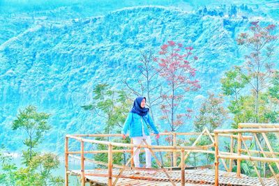 Full length of woman standing by railing at observation point against mountain