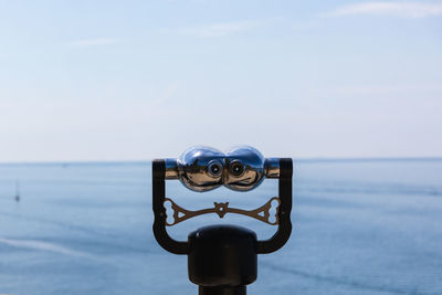 Close-up of coin-operated binoculars against sea