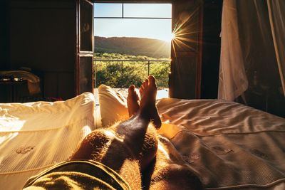 Low section of man relaxing on bed