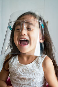 A toddler girl wearing the face protection shield. a safety corona mask during covid-19 pandemic.