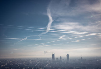 Aerial view of vapor trails over buildings in city