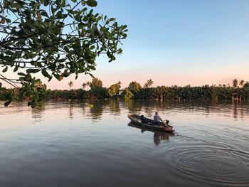 People on boat in lake against sky