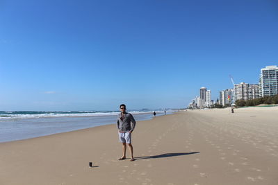 Rear view of woman on beach against clear sky