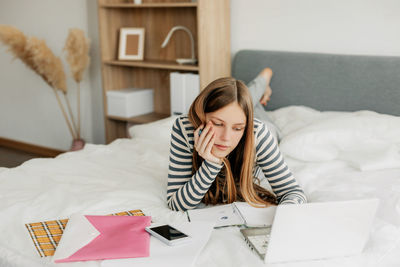 A tired student is preparing for a difficult exam at home using a laptop. modern technologies 