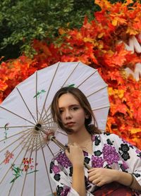Portrait of beautiful young woman standing by plants during autumn