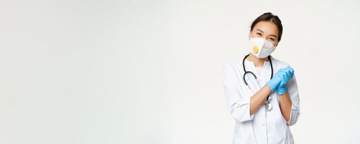 Portrait of female doctor standing against white background