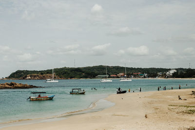 Sailboats moored on beach against sky