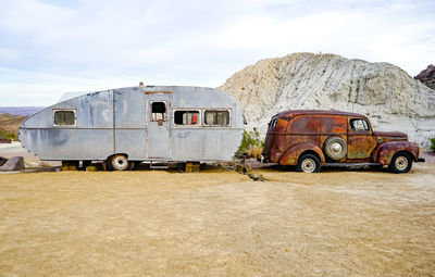 Abandoned and trailer on field against sky