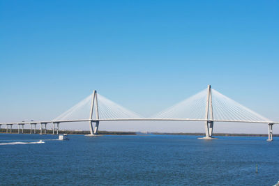 Bridge over calm sea against clear blue sky