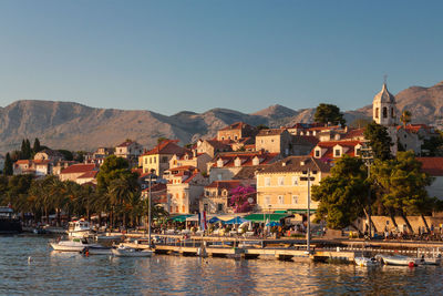 Buildings by sea against clear sky