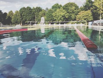 Swimming pool by trees against sky