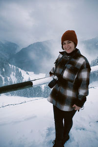 Portrait of smiling man standing on snowcapped mountain against sky