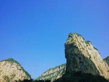 Low angle view of mountain against blue sky