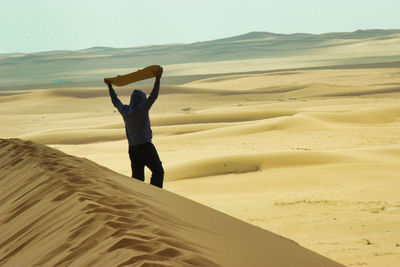 Full length of woman standing on sand at desert