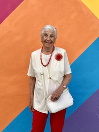 Portrait of smiling woman standing against wall