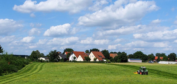 Agricultural field by town against cloudy sky