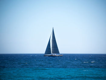 Sailboat sailing in sea against clear sky