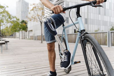 Low section of man with artificial limb riding bicycle in city