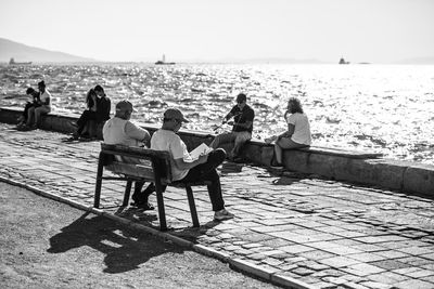 People sitting on chair at beach against sky