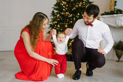 New year and christmas. mom and dad hold hands with their little son  christmas tree