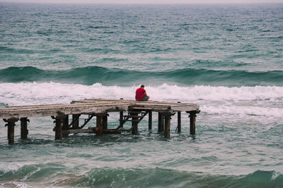 Rear view of man sitting on shore